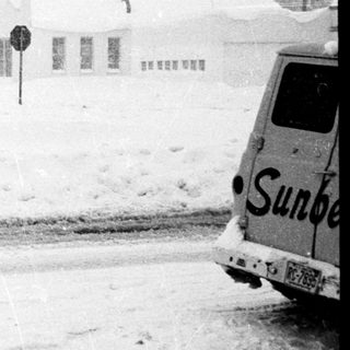 Snow-covered small town gas station and buildings.