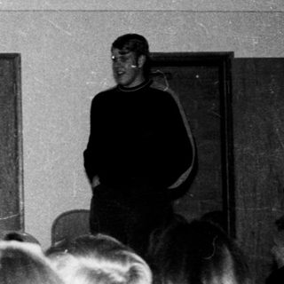 Classroom lecture with students listening and two speakers.