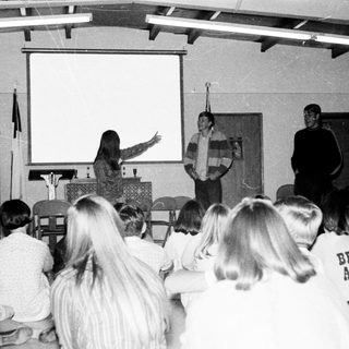Classroom lecture with students listening and two speakers.