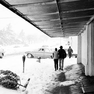 Snowy street scene with people walking under shelter.