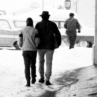 Snowy street scene with people walking under shelter.