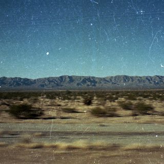 Desert landscape with distant mountains under starry sky.