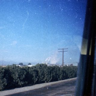 Rural roadside view with greenery, power lines, and distant haze.