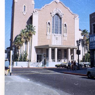 Historic building with vintage cars, palm trees, and "Avalon Cleaners" sign.