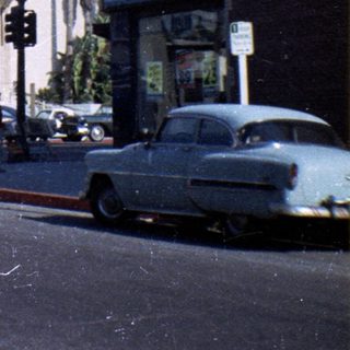 Historic building with vintage cars, palm trees, and "Avalon Cleaners" sign.