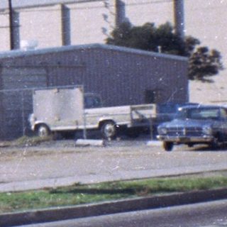 Industrial area with parked vehicles and warehouses.