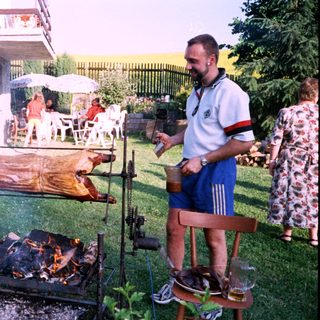 Whole pig roasting over backyard fire.