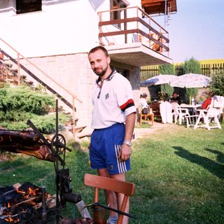 Man grilling meat outdoors in backyard.