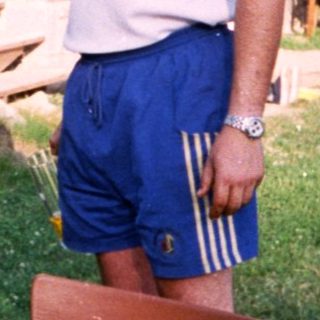 Man grilling meat outdoors in backyard.
