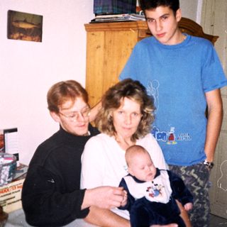 Family posing together indoors with a baby.