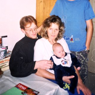 Family posing together indoors with a baby.
