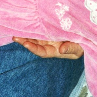 Baby wearing pink onesie, held by adult.