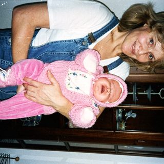 Woman holding pink teddy bear doll.