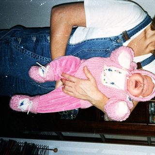 Woman holding pink teddy bear doll.