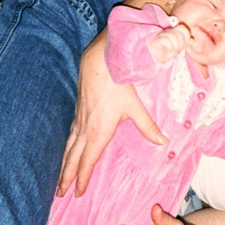 A woman cradles a baby in pink clothing.
