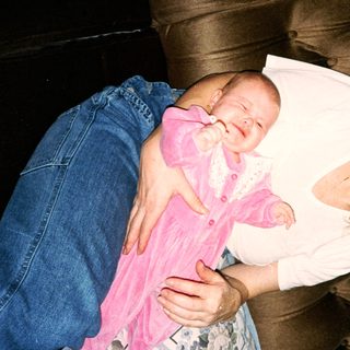 A woman cradles a baby in pink clothing.