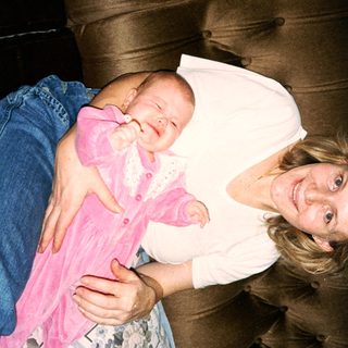 A woman cradles a baby in pink clothing.