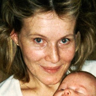 A woman holding a baby in pink dress.