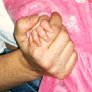A woman holding a baby in pink dress.