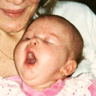 A woman holding a baby in pink dress.