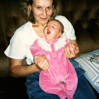 A woman holding a baby in pink dress.