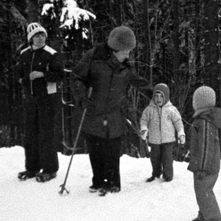 People skiing and standing in snowy forest.