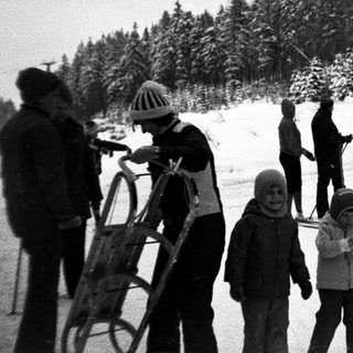 Family skiing and sledding in snowy forest.