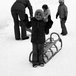 People sledding on snow-covered hill.