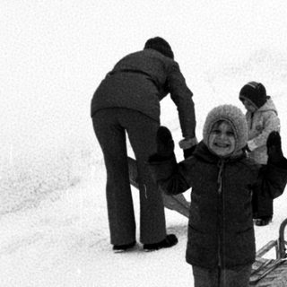 People sledding on snow-covered hill.