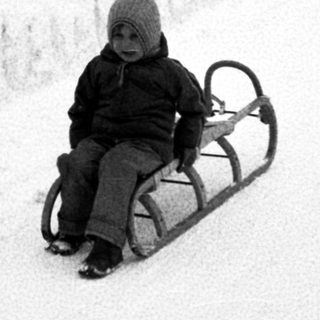 Child sledding down snow-covered hill.