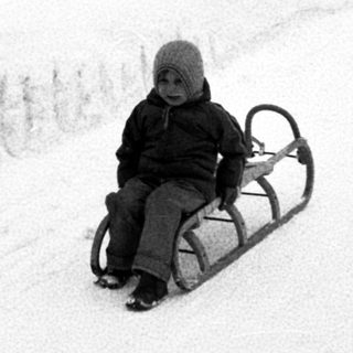 Child sledding down snow-covered hill.