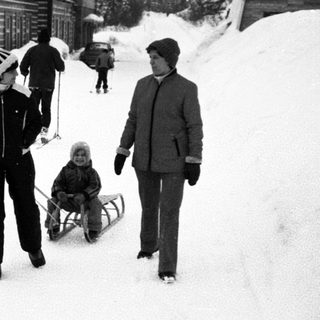 Snowy outdoor scene with people sledding and walking.