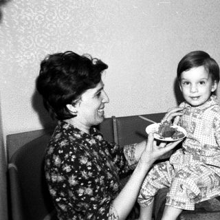 A woman feeding a young child indoors.