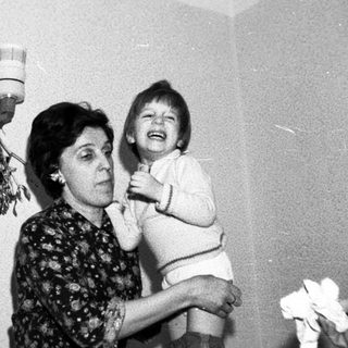 A woman holding a laughing child indoors.