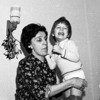 A woman holding a laughing child indoors.