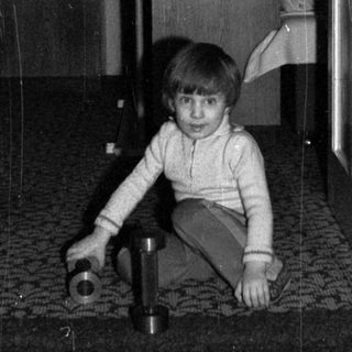 Child playing with toy on tiled floor indoors.