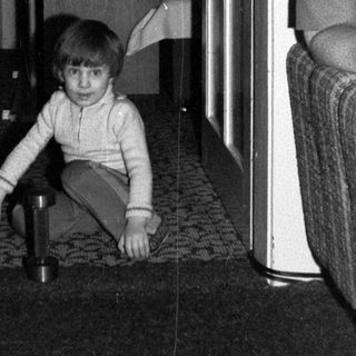 Child playing with toy on tiled floor indoors.
