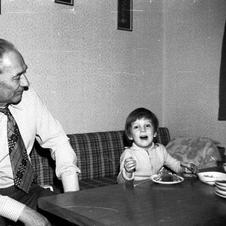 Older man and young child sharing a meal indoors.