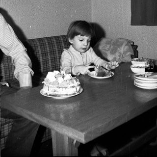 Child blowing out birthday cake candles indoors.