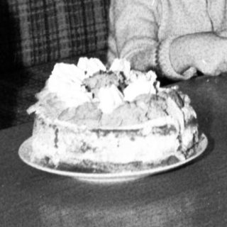 Child blowing out birthday cake candles indoors.