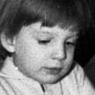 Child blowing out birthday cake candles indoors.