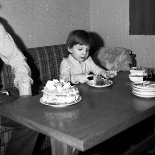Child blowing out birthday cake candles indoors.