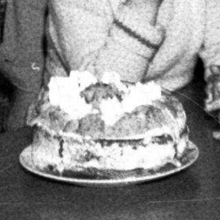 Family celebrating birthday with cake indoors.