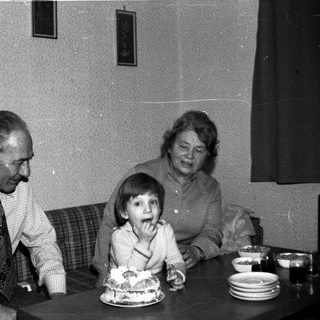 Family celebrating birthday with cake indoors.
