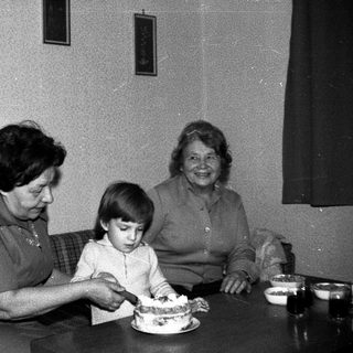Family sharing birthday cake indoors.