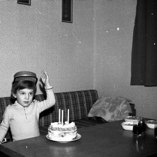 Child wearing hat blows out birthday cake candles.