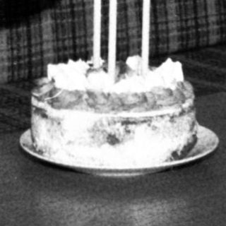 Child wearing hat blows out birthday cake candles.