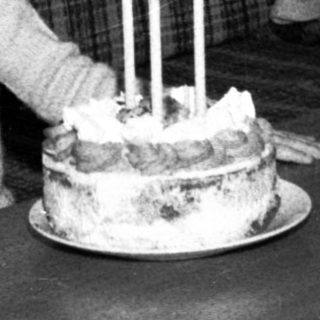 Child sitting by cake with lit candles.