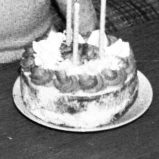 Young child surprised by birthday cake with lit candles.