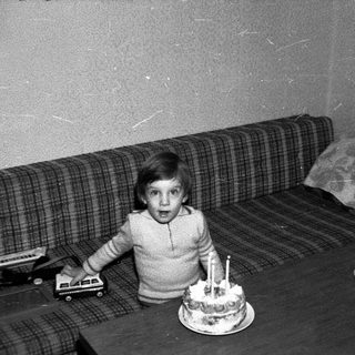 Young child surprised by birthday cake with lit candles.
